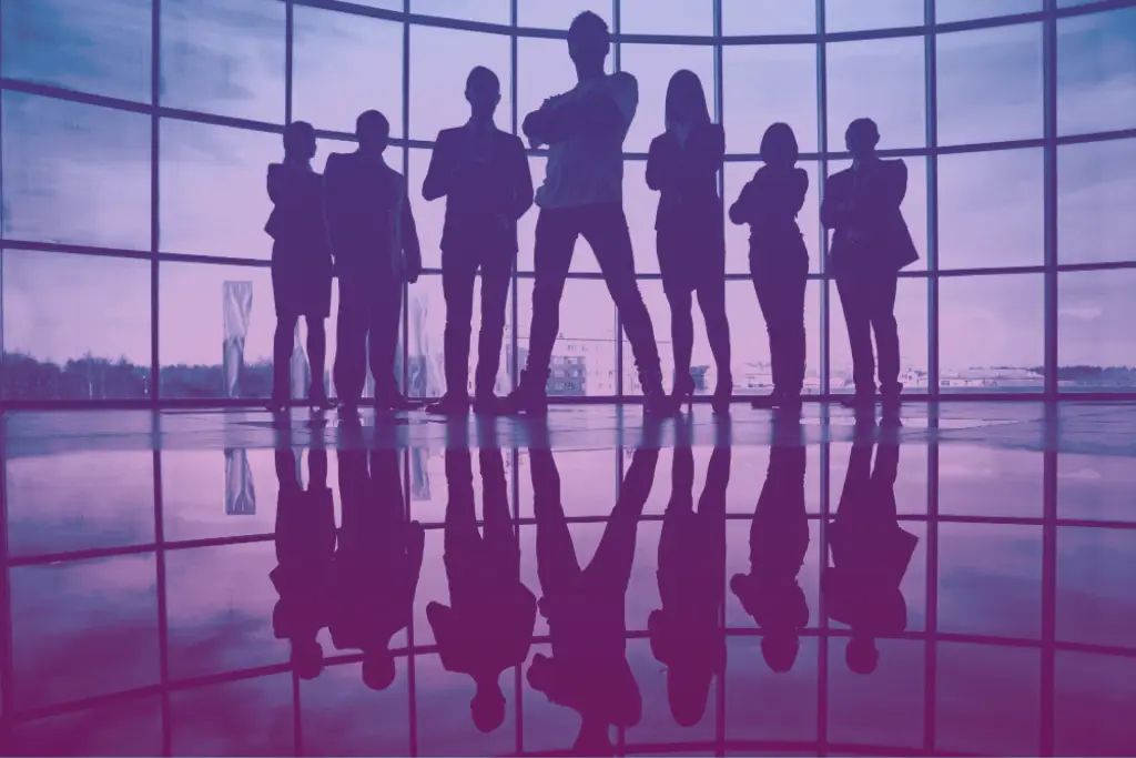 Silhouettes of a professional team standing in front of large windows, representing leadership, strategy, and teamwork.